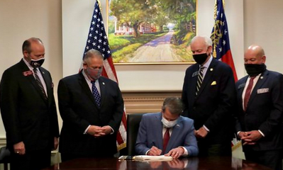 Georgia Governor Brian Kemp shown above signing voter suppression bill S.B. 202.